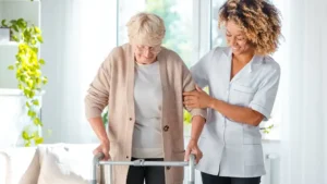 Elderly person with dementia using a walking aid, supported by a nurse, highlighting concerns about aluminum causing dementia.