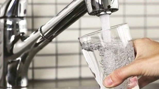 Tap water running from a kitchen faucet at home, raising concerns about aluminum in water.