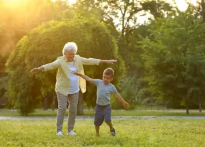 Grandmother and grandchild playing happily in a garden, representing the connection between autism and Alzheimer's across generations.