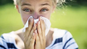 Young girl sneezing with a runny nose, raising concerns about the connection between vaccines and allergies