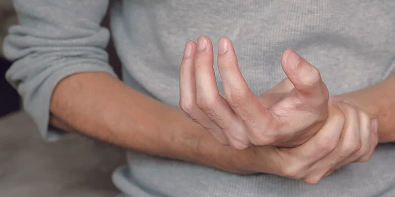 Man holding his hands in pain due to an autoimmune disease, highlighting concerns about the role of aluminum in autoimmune diseases