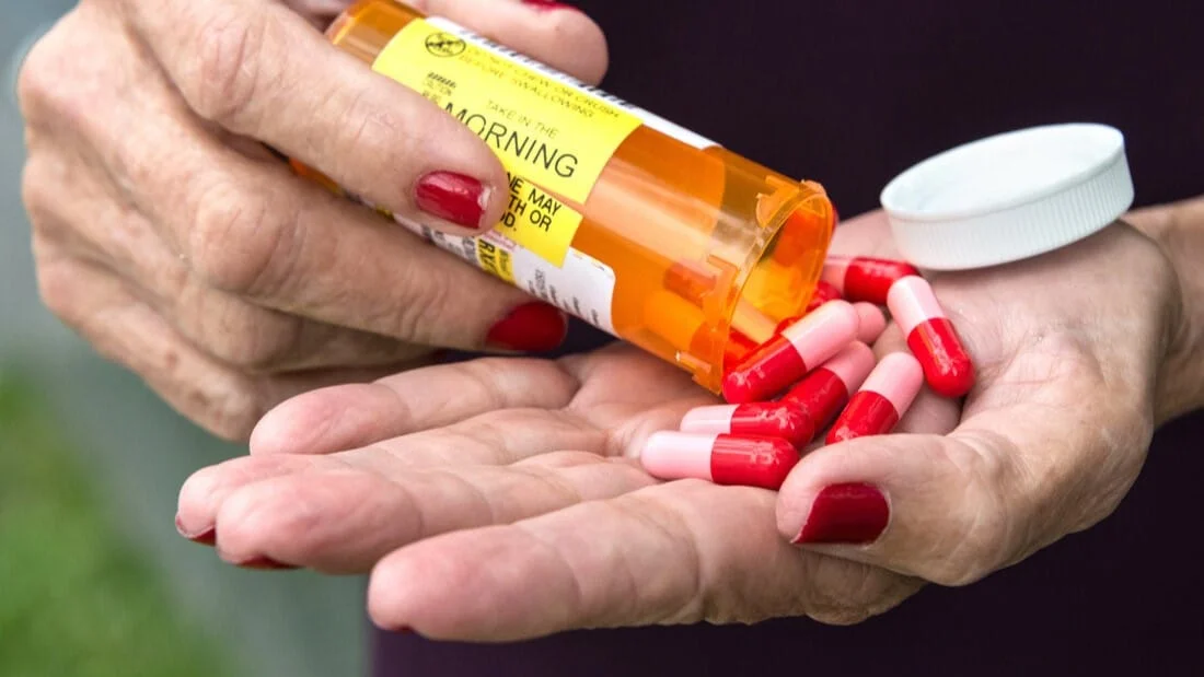 Elder pouring aluminum-containing medication from a bottle, highlighting aluminum in medications