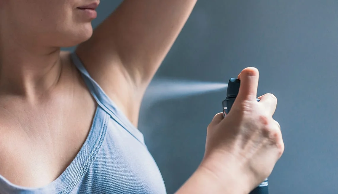 Woman spraying aluminum-containing deodorant, highlighting aluminum use in cosmetics